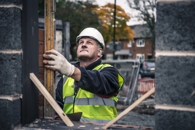 a builder checking whether a wall is level using a spirit level