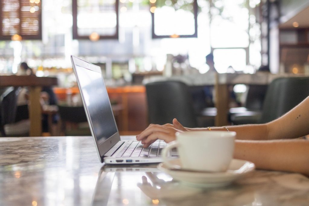 a person enjoying a cup of coffee while typing on a laptop